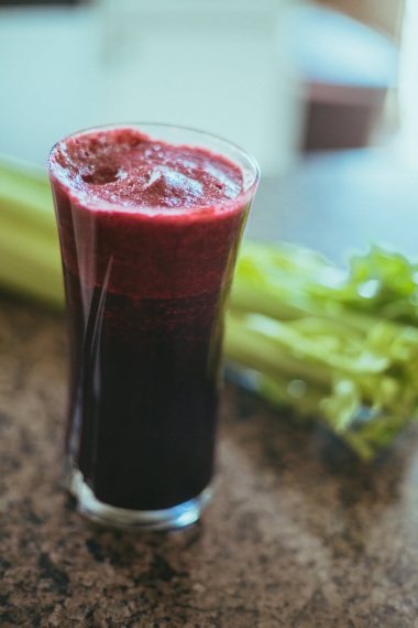 Pre-workout Dark red energy smoothie with celery by its side on top of kitchen countertop